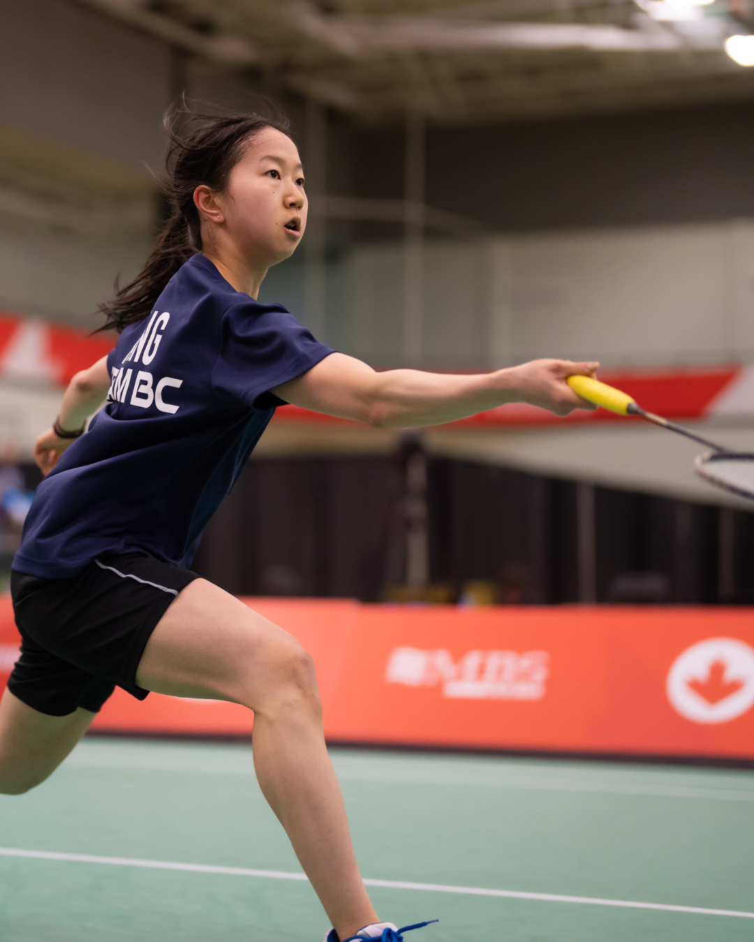 Badminton player lunges for bird