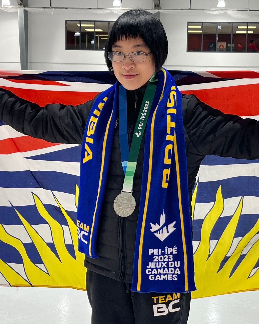 Figure skater poses with BC flag and silver medal