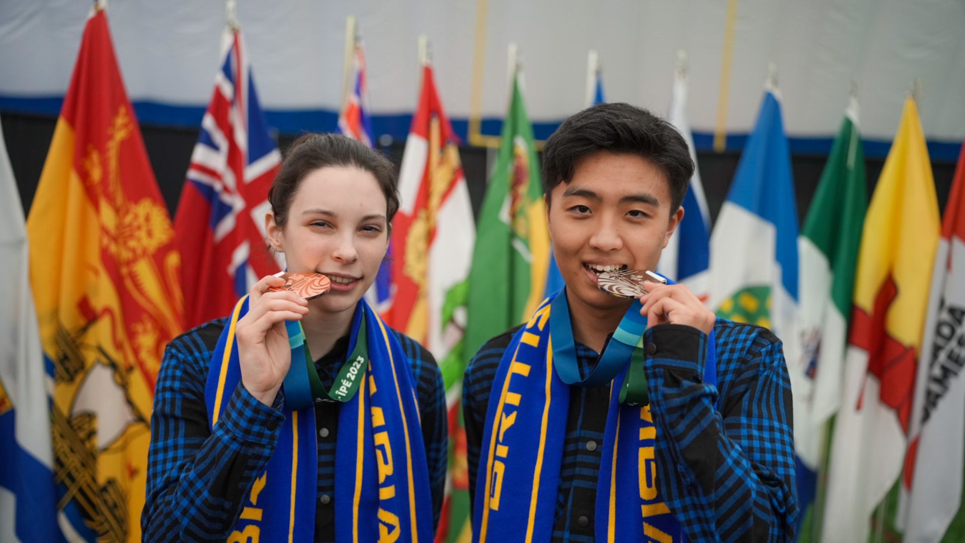 Two Karate athletes bite their medals.