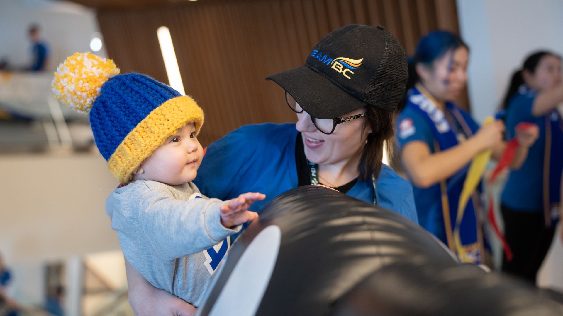 Ringette coach holds baby at the 2023 Canada Winter Games