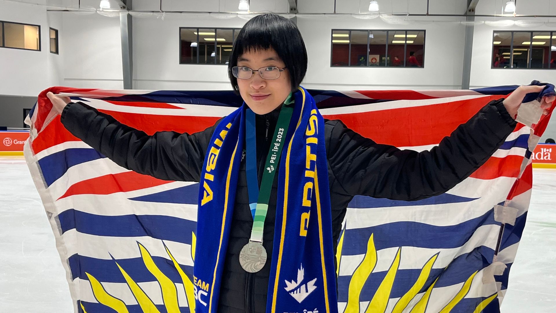 Figure skater poses with BC flag and silver medal